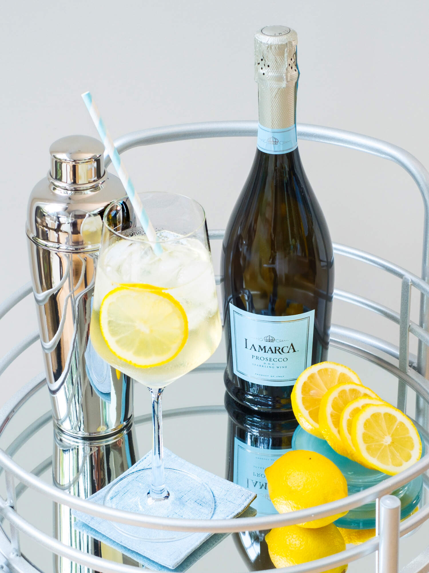 bottle of La Marca on a wine cart with glass of spritz and lemons