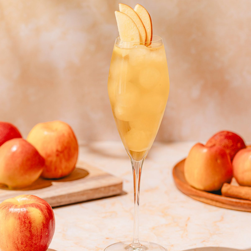 A class of Fall Cocktail with apples around it