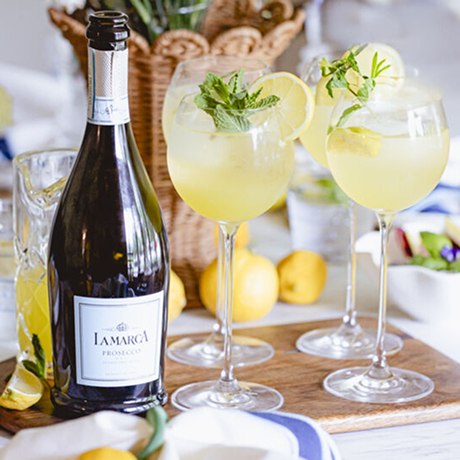 Bottle of La Marca, with three cocktails with lemon